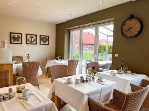 a restaurant with tables and chairs with a clock on the wall at Hotel Grachtenhuus Greetsiel in Greetsiel