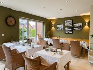 a restaurant with tables and chairs and a clock on the wall at Hotel Grachtenhuus Greetsiel in Greetsiel