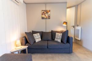 a living room with a blue couch in a room at Delya, chalet confort, climatisation, piscine in Agde