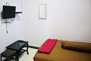 a bedroom with a bed and a table and a television at Homestay Reyna in Ende Airport