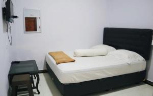 a small bed in a room with a table at Homestay Reyna in Ende Airport