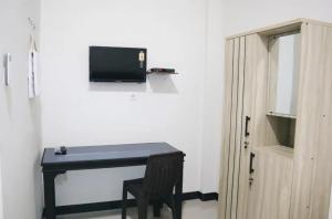 a desk with a television on a wall next to a door at Homestay Reyna in Ende Airport +7 photos