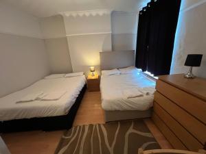 two beds in a small room with a window at Cozy Spacious Flat in South Norwood