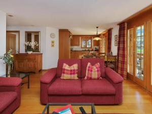 a living room with a red couch and a kitchen at Apartment Chalet Nagano by Interhome in Grindelwald