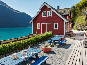 a red house with a picnic table next to a lake at Apartment Vardeheii by Interhome in Arnefjord