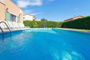 a swimming pool with blue water in front of a house at Villa Ana by Rent Istria in Vilanija