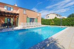 a swimming pool with chairs and a house at Villa Ana by Rent Istria in Vilanija