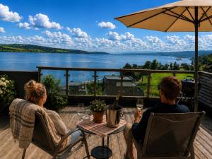 a man and woman sitting at a table under an umbrella at Eksklusiv hytte, Utsikt, ro og høy komfort in Gjøvik