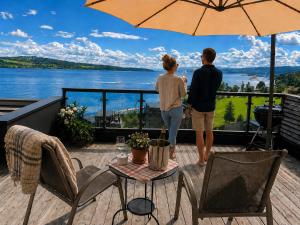 a man and woman standing on a deck with an umbrella at Eksklusiv hytte, Utsikt, ro og høy komfort in Gjøvik