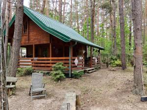 a log cabin in the woods with a chair in front of it at Szumi szumi LAS in Joniec