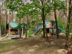 a tree house in the woods with a slide at Szumi szumi LAS in Joniec