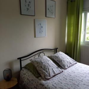a bedroom with a bed with two pillows and a window at L'ABRI in May-sur-Orne