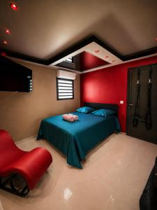 a bedroom with a blue bed and a red wall at Love room Coconut Secret in Le Gosier