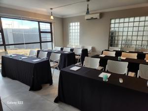 a room with black tables and chairs and windows at Pado B & B in Gqeberha +50 photos