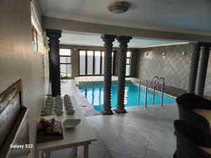 a swimming pool with columns in a house at Pado B & B in Gqeberha