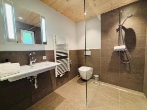 a bathroom with a shower and a sink and a toilet at Pension Bergheim in Tannheim
