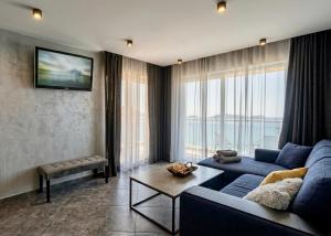 a living room with a blue couch and a large window at AGATA BEACH Boutique -Adult Only in Ahtopol