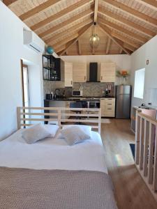 a bedroom with a white bed and a kitchen at Villa Barbosa in Quintiães