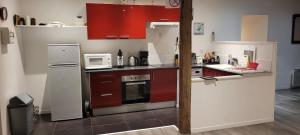 a kitchen with red cabinets and a white refrigerator at Gîte de Préaux in Tousson +5 photos