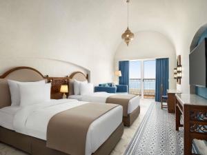 a hotel room with two beds and a television at Movenpick Resort Sharm El Sheikh in Sharm El Sheikh +233 photos