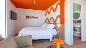 a bedroom with a white bed and an orange wall at Kyriad - Royan Plage in Royan