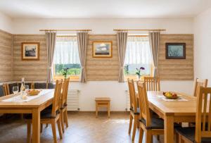 a dining room with wooden tables and chairs and windows at Andrejkin dom in Blatnica