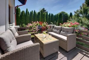 a patio with wicker chairs and tables and flowers at JD Apartamenty - Klimatyzacja, basen, parking i wifi w cenie in Mysłakowice