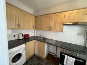 a kitchen with wooden cabinets and a washing machine at Cozy Spacious Flat in South Norwood +10 photos