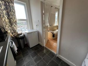 a room with a hallway with a couch and a window at Cozy Spacious Flat in South Norwood