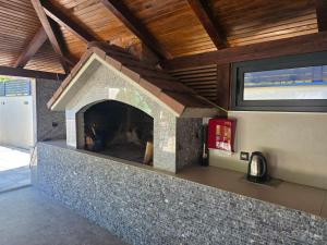 a stone fireplace in a house with a wooden ceiling at Vacation Home Belluna in Račić
