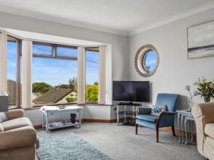 a living room with a couch and a tv and windows at Kents Bank Holiday - Pet Friendly with Bay Views in Grange Over Sands