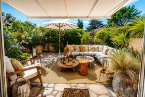 an outdoor patio with a couch and an umbrella at Solenzia, appartement luxueux à 100m de la plage in Saint-Tropez