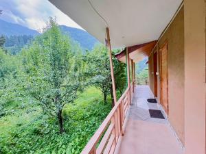 a balcony of a house with a view of the mountains at Flamingo Aur Maina Stays - Jibhi in Jibhi