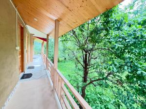 an empty porch of a house with a tree at Flamingo Aur Maina Stays - Jibhi in Jibhi