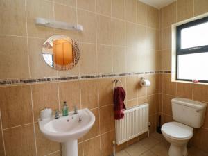 a bathroom with a sink and a toilet and a mirror at Strand House in Bannow +16 photos