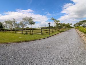 an empty road with a fence and grass at Strand House in Bannow