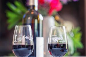 two glasses of red wine next to a bottle of wine at Grésigne in Larroque