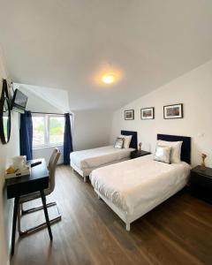 a hotel room with two beds and a desk and a desk at Hôtel Le Vauban in Carentan