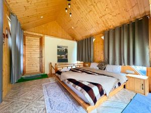 a bed in a room with a wooden ceiling at Flamingo Aur Maina Stays - Jibhi in Jibhi