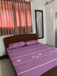 a bed in a room with purple sheets and a mirror at Courtyard Hostel Negombo in Negombo