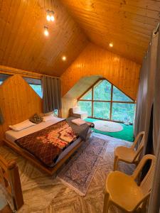 a bedroom with a large bed and a large window at Flamingo Aur Maina Stays - Jibhi in Jibhi +22 photos