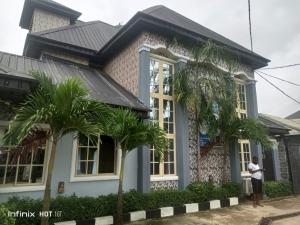 a man standing in front of a house with palm trees at Pleasure rest hotel and suites in Uyo
