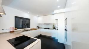 a white kitchen with a sink and a refrigerator at Solstice Villa Private Pool & BBQ Cascais in Alcabideche +18 photos