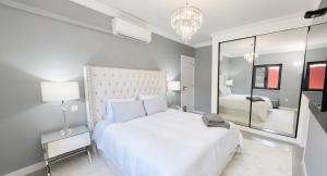 a white bedroom with a large bed and a mirror at Solstice Villa Private Pool & BBQ Cascais in Alcabideche