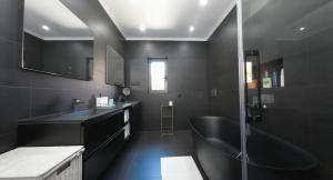a black bathroom with a sink and a shower at Solstice Villa Private Pool & BBQ Cascais in Alcabideche