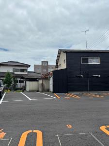 a parking lot with a black building in a parking lot at ビジネスホテルinn in Kashima