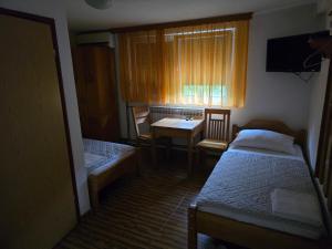 a small room with two beds and a table and a window at Vila PAUN in Doboj +6 photos