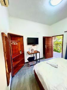 a bedroom with a bed and a desk with a television at Residencial Nyelete in Vilanculos +25 photos