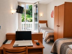 a hotel room with a desk with a laptop on it at Hôtel Compostelle in Lourdes