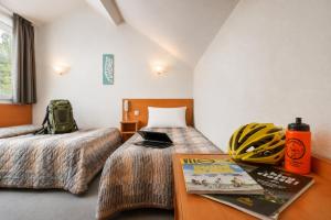 a room with two beds and a table with a book at Hôtel Compostelle in Lourdes +43 photos